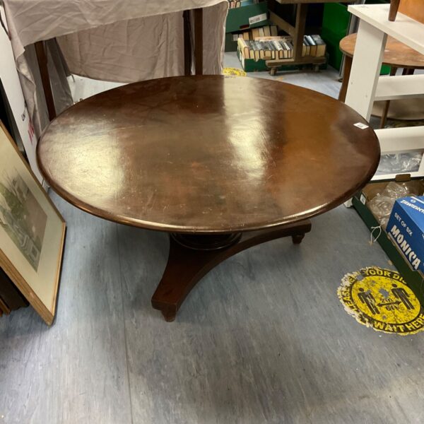 Antique mahogany tilt top table with carved legs in a vintage setting.