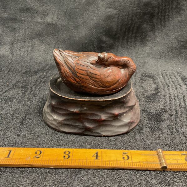 Antique pewter okimono of a recumbent goose on a hardwood stand.