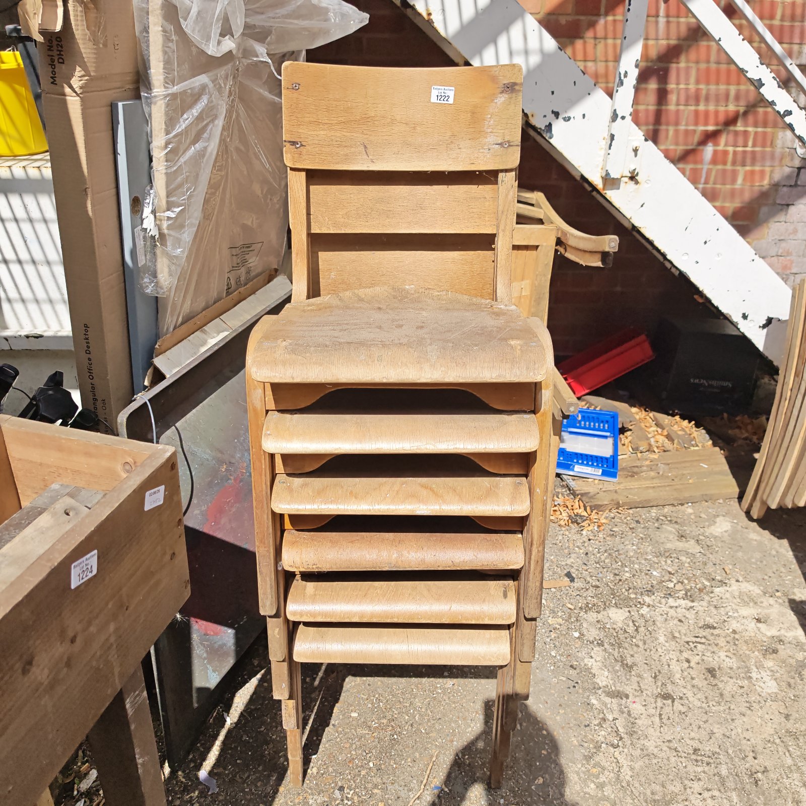 Stack of antique wooden school chairs with visible wear.