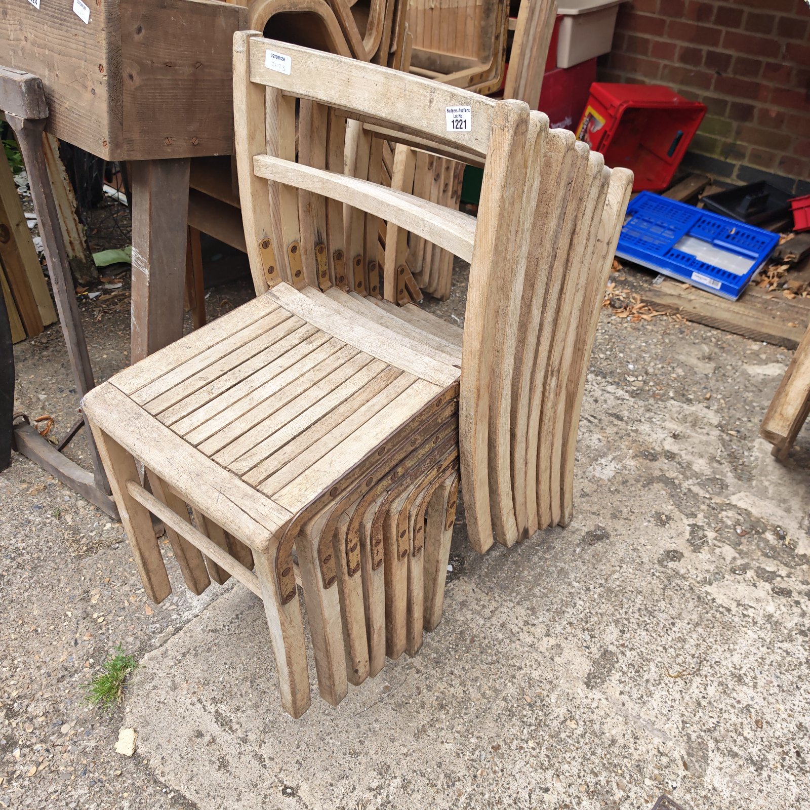 Antique wooden school stacking chairs in a garden setting.