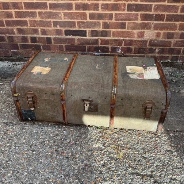 Antique steamer trunk with brown canvas and metal details.
