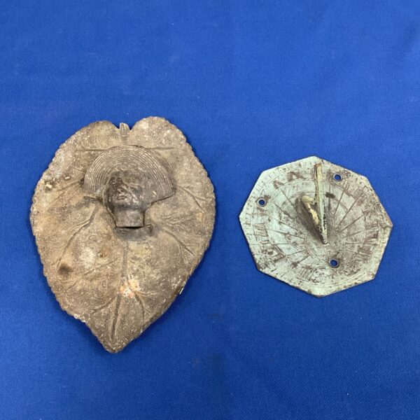 Antique cast metal sundial shaped like a tobacco leaf.
