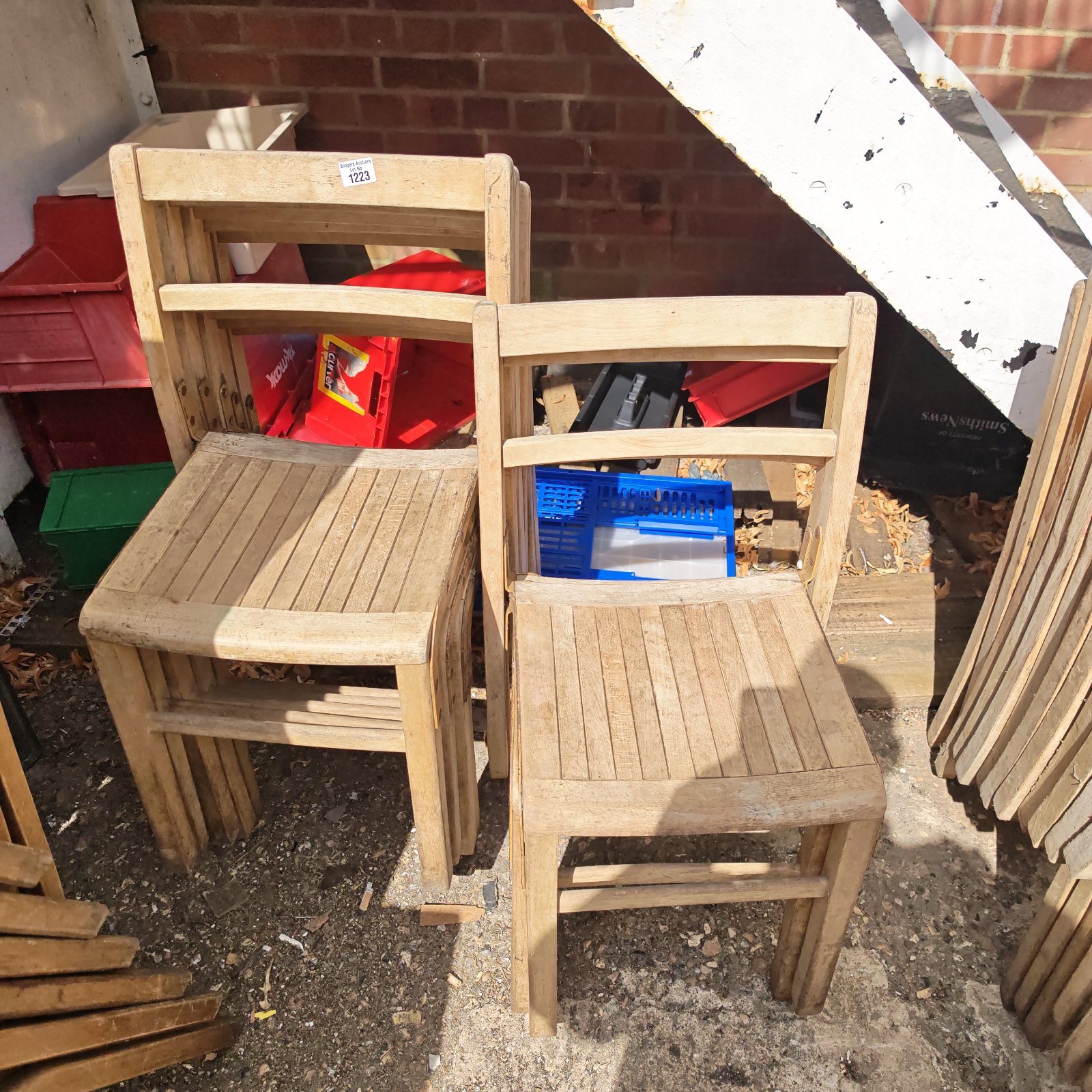 Lot of seven antique wooden stacking chairs stacked together.