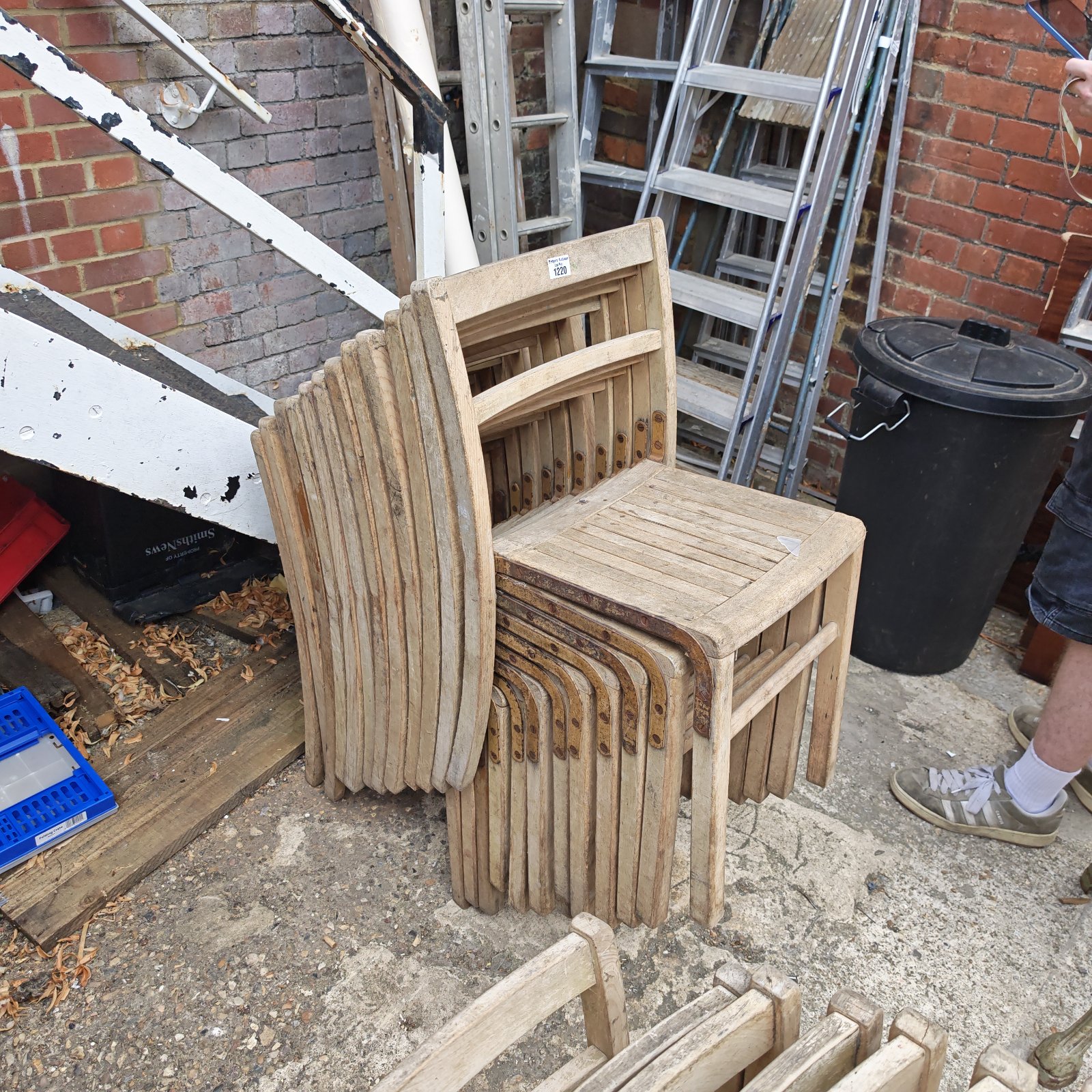 Lot of twelve antique wooden stacking chairs stacked together.