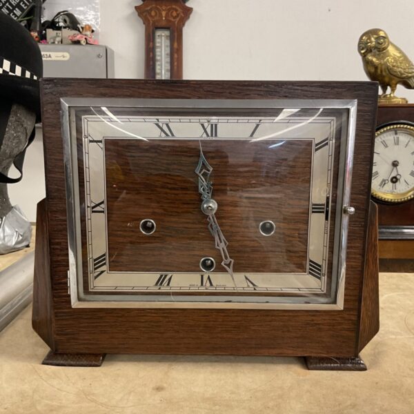 Vintage Art Deco mantle clock with a dark wood case and cream face.