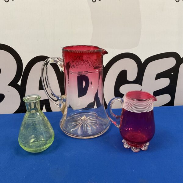 Vintage art glass collection featuring a cranberry pitcher and green glass.