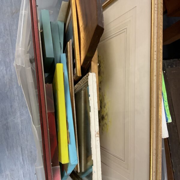 Crate of assorted vintage and decorative picture frames for wall decor.