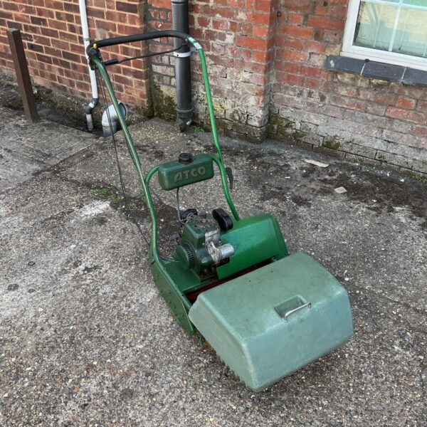 Vintage Atco lawnmower in green, showing signs of age.
