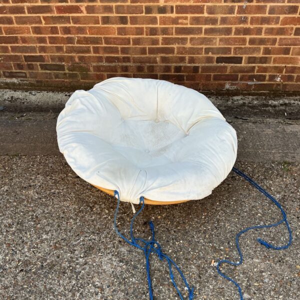 Vintage bamboo swing seat with cream cushion in a garden setting.