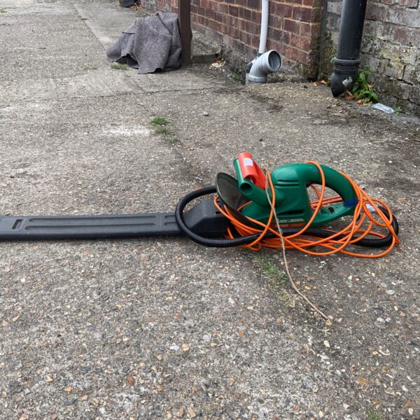 Black and Decker electric hedge trimmer for garden maintenance, showing wear.