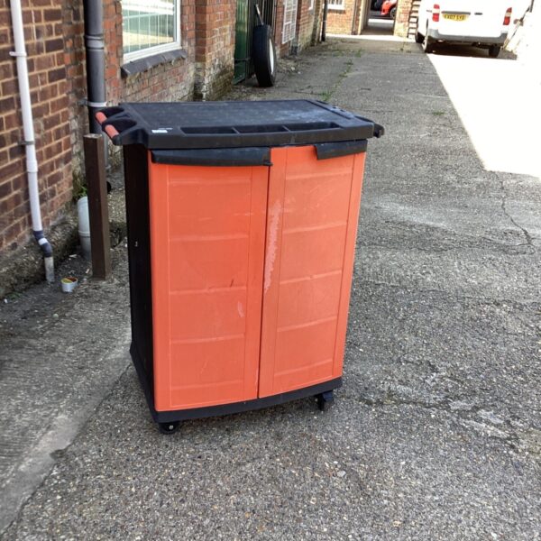 Orange and black Black and Decker tool box on wheels in a yard.