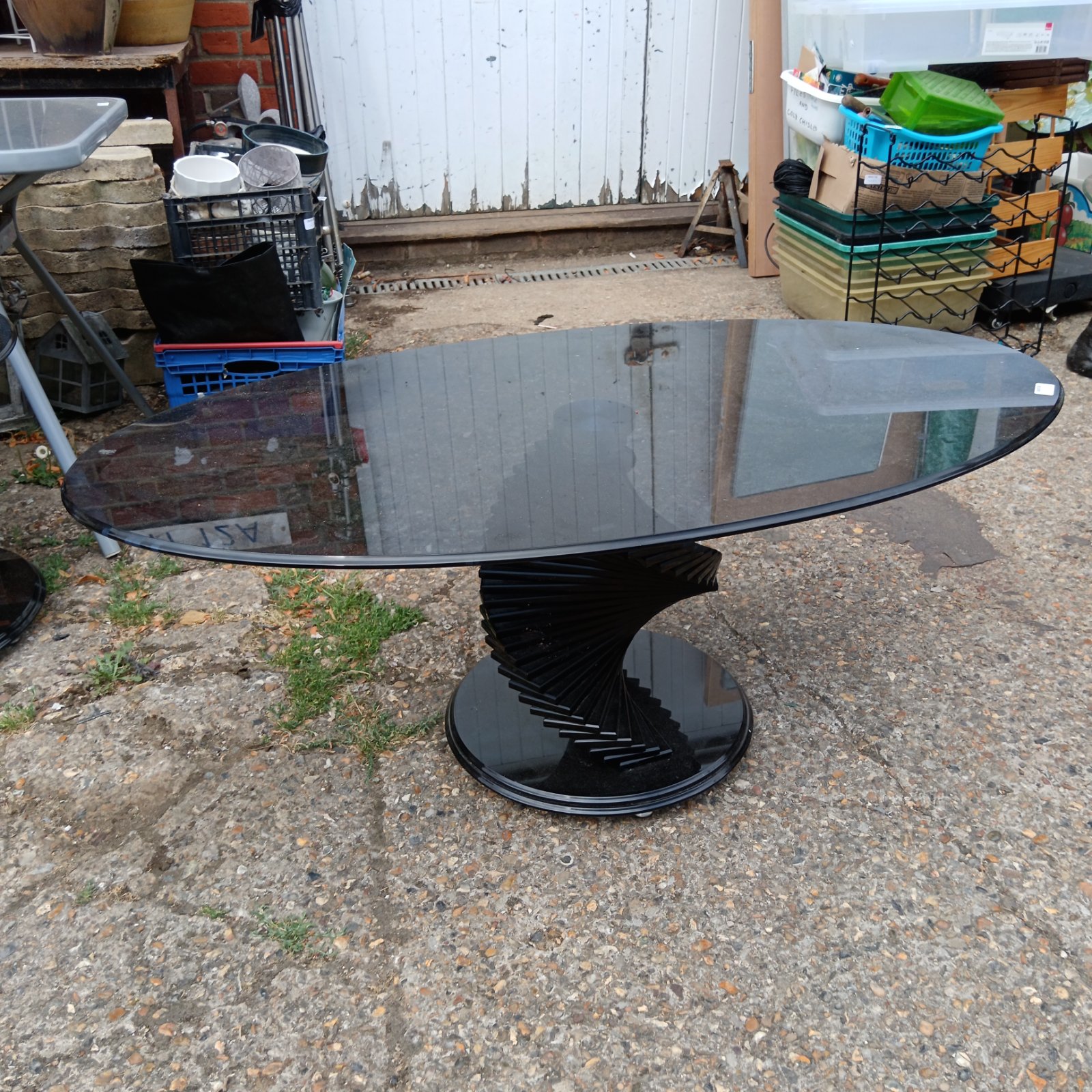 Black designer oval coffee table with spiralling pedestal base.