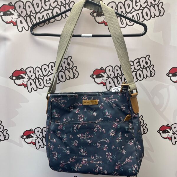 Brakeburn crossbody bag with blue floral pattern and canvas strap.