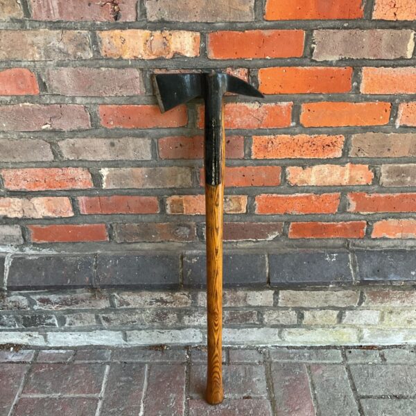 Antique British Rail fire axe against brick wall.