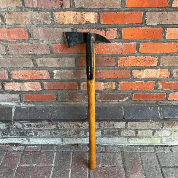Vintage British Rail carriage fire axe against brick wall.