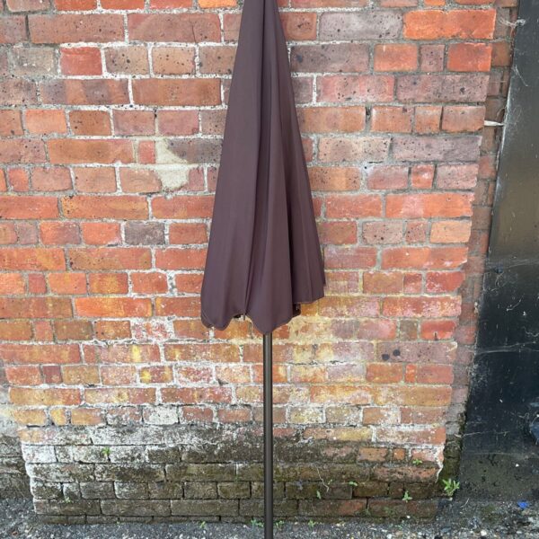 Brown garden umbrella standing outdoors, providing shade.