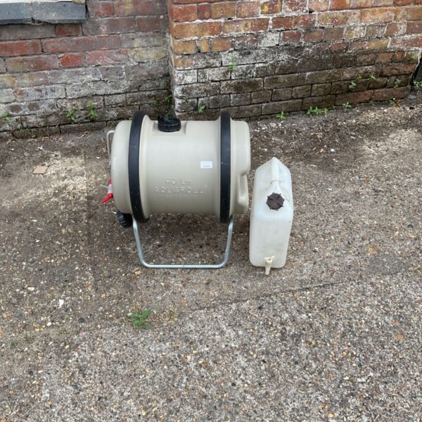 Plastic camping water barrel with tap, showing signs of wear.