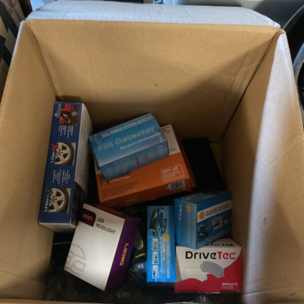 Box of assorted car parts including brake pads and a headlight.