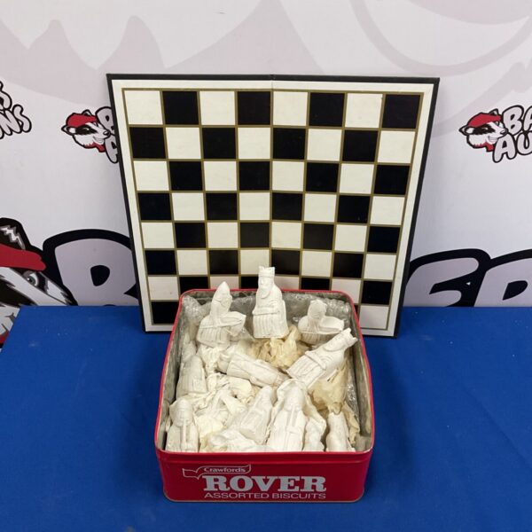 Vintage chess set with white plaster pieces on a chessboard.