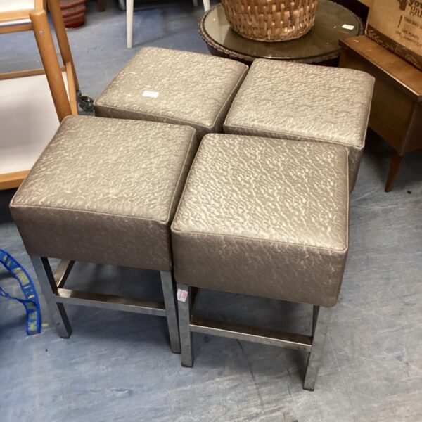 Set of four chrome bar stools with neutral seats.