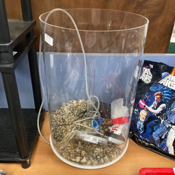 Clear circular fish tank with gravel and filter accessories.