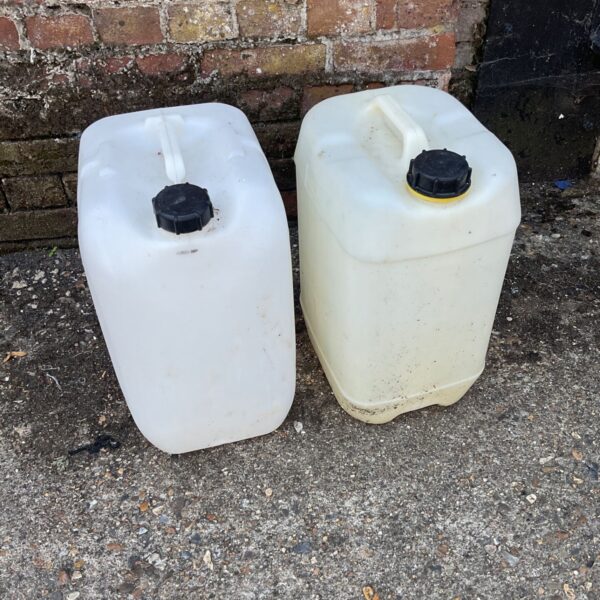 Two clear plastic liquid storage bottles with black caps.