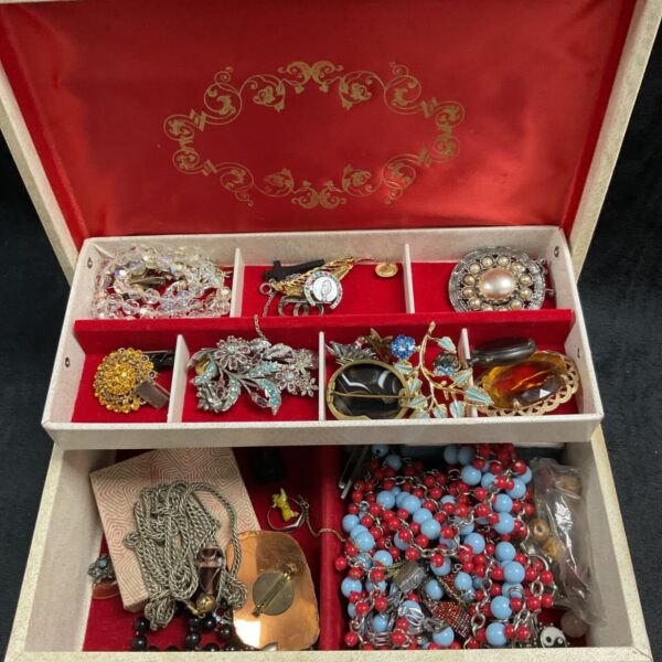 Costume jewellery box filled with vintage necklaces and brooches.