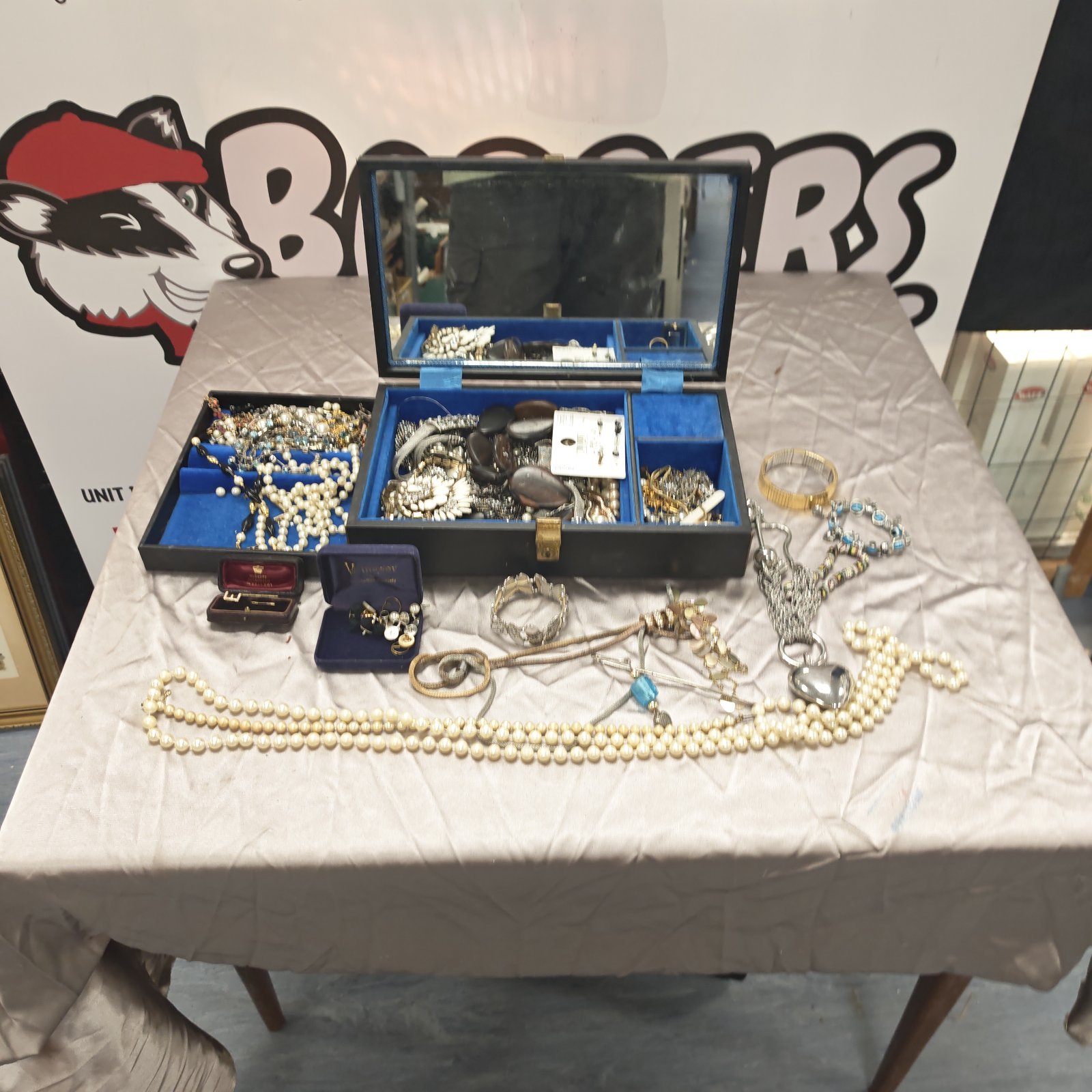 Mirrored jewellery box filled with vintage costume jewellery and beaded necklaces.