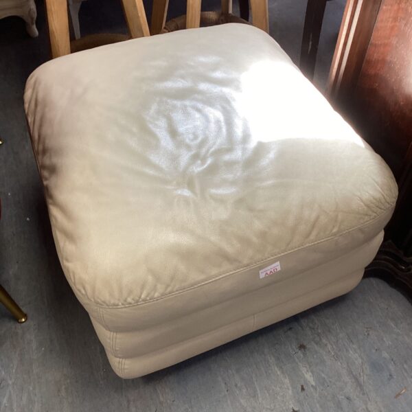 Cream leather pouffe with a rounded shape and vintage style.
