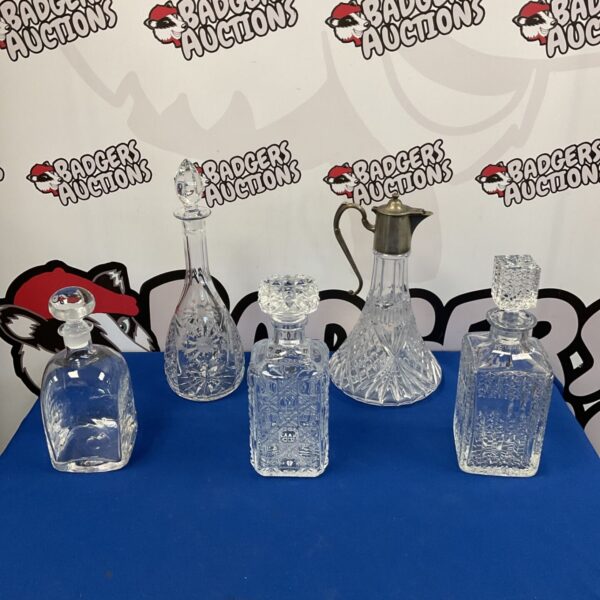 Four lead crystal decanters including a silver topped ewer.