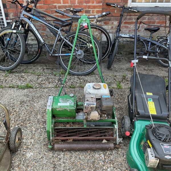 Vintage cylinder lawn mower with a bicycle in the background.