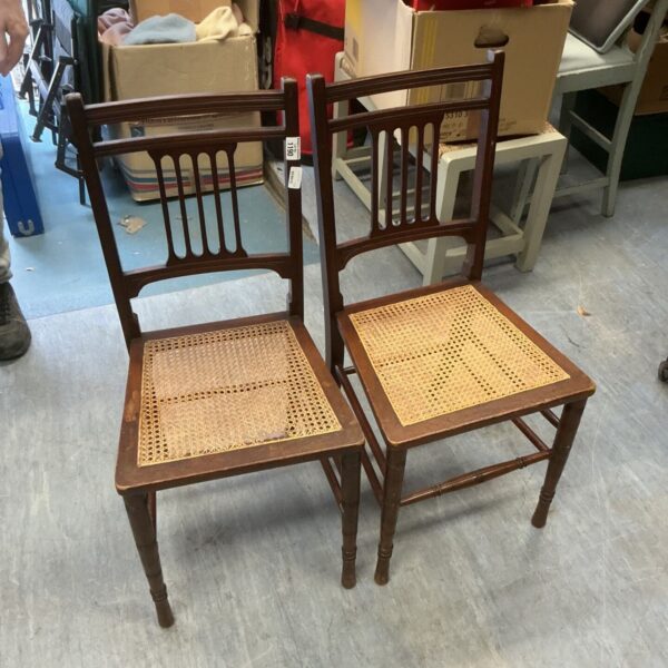 Pair of antique Edwardian hall chairs with woven seats needing restoration.