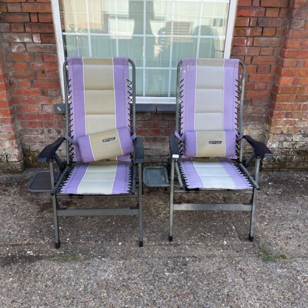 Two Elite folding deckchairs with side tables in a garden setting.