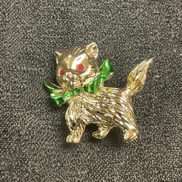 Vintage enamel kitten brooch with green ribbon and red eyes.
