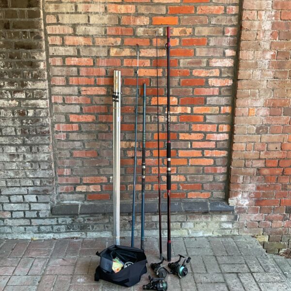 Fishing rods and reels lot displayed against a brick wall.