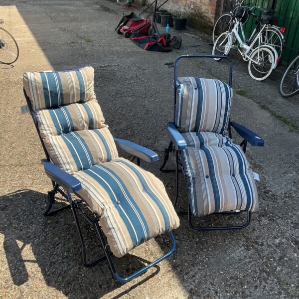 Two striped folding garden chairs in a garden setting.