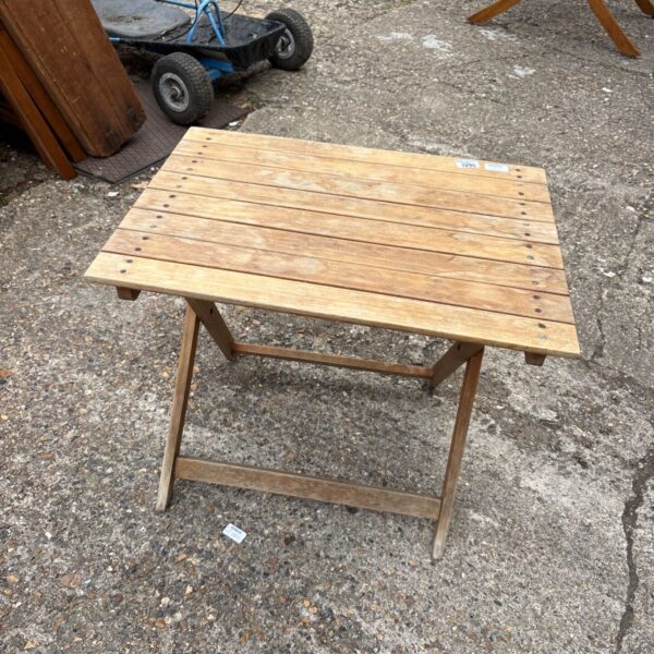 Small wooden folding garden table in a garden setting.