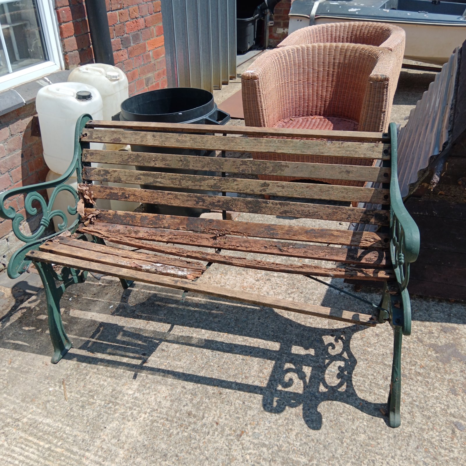 Weathered wrought iron garden bench awaiting restoration.