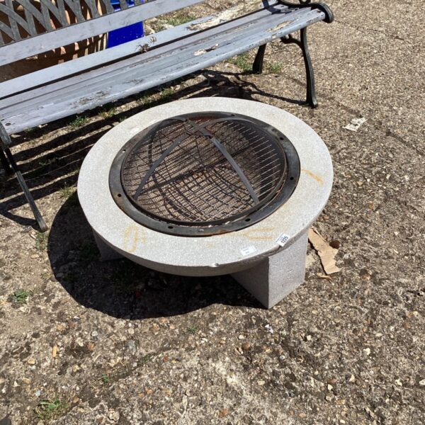 Metal garden firepit with mesh screen in a backyard setting.