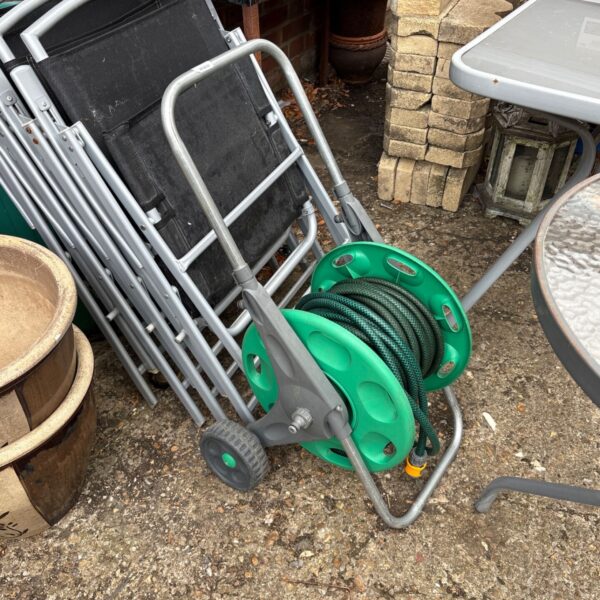 Wheeled garden hose reel in outdoor setting.