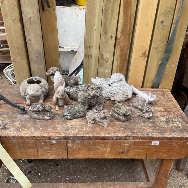 Collection of weathered concrete garden ornaments with animal figurines.