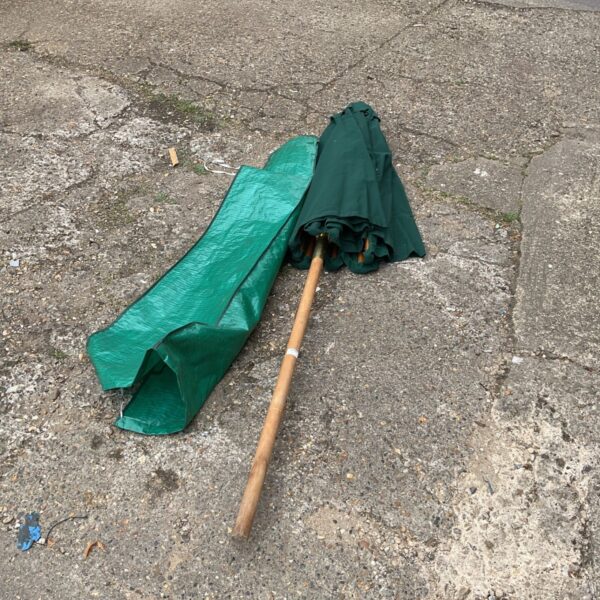 Large green garden parasol with wooden pole, providing outdoor shade.