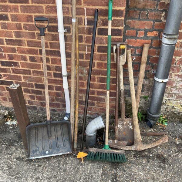 Bundle of used garden tools including shovels and a rake.