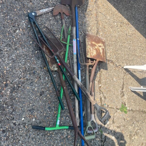 A lot of vintage garden shovels and digging tools.