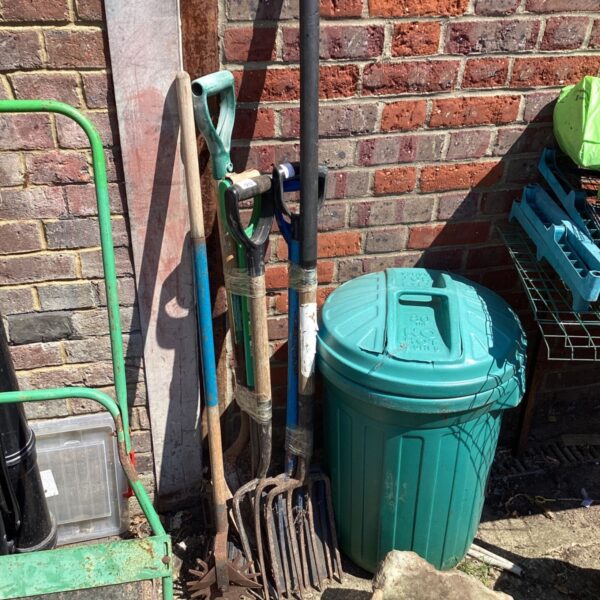 Selection of used garden tools and a plastic bin for outdoor storage.