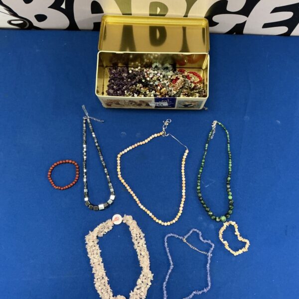 Tin filled with colourful gemstone necklaces and bracelets.