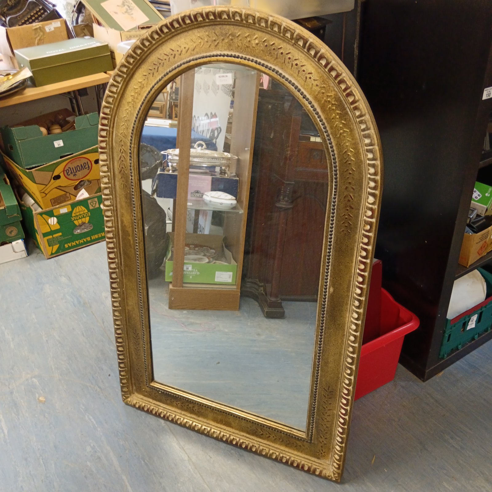 Large gilt framed arch mirror with ornate detailing.