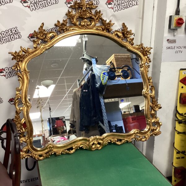 Ornate gilt wall mirror in Rococo style, detailed frame.