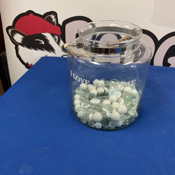 Clear glass jar filled with pale blue glass beads for home decor.