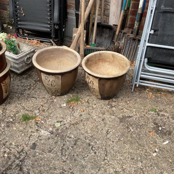 Two vintage glazed terracotta garden planters in a garden setting.